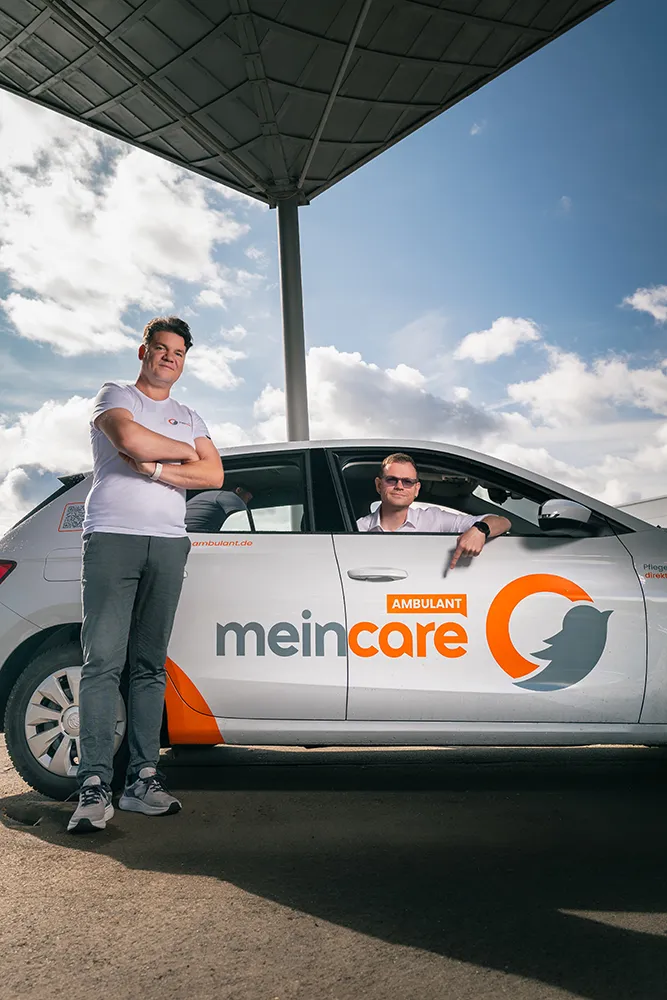 Pflegekraft von meinCare Ambulant am Dienstwagen